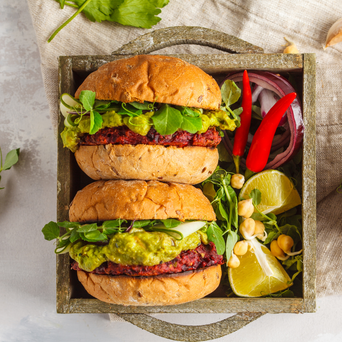 Two beet & black bean burgers with guacamole and microgreens for a plant-based diet.