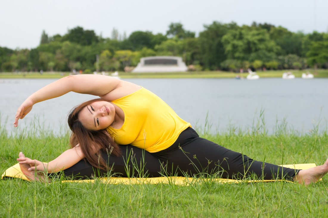 smiling woman doing a sideways stretch in a park